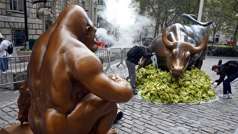 Gorilla statue in front of the Wall Street bull statute in New York City.